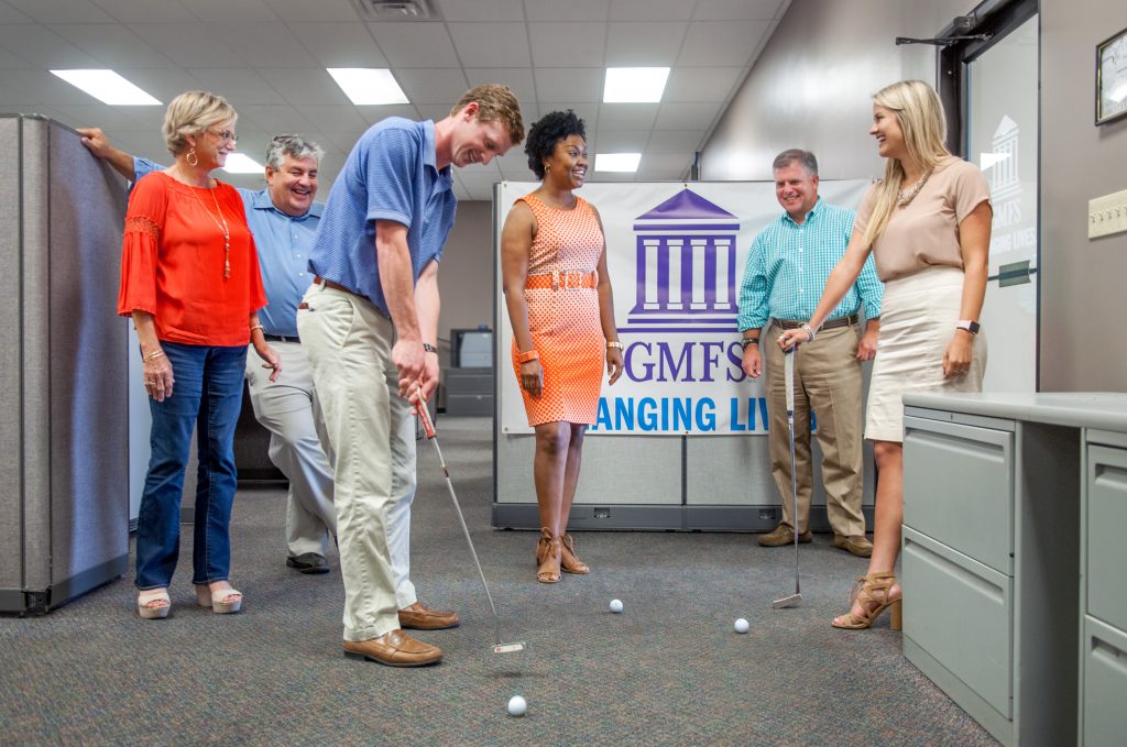 GMFS employees taking a break playing putt putt