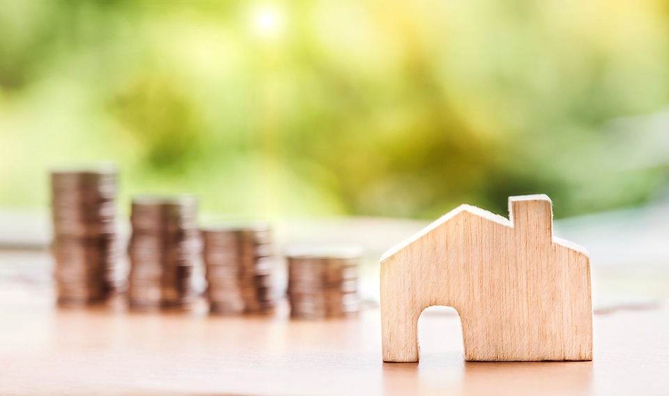 Graphic depicting a small wooden house next to a stack of gold coins
