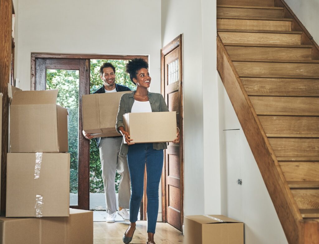 Young couple carrying boxes into new home