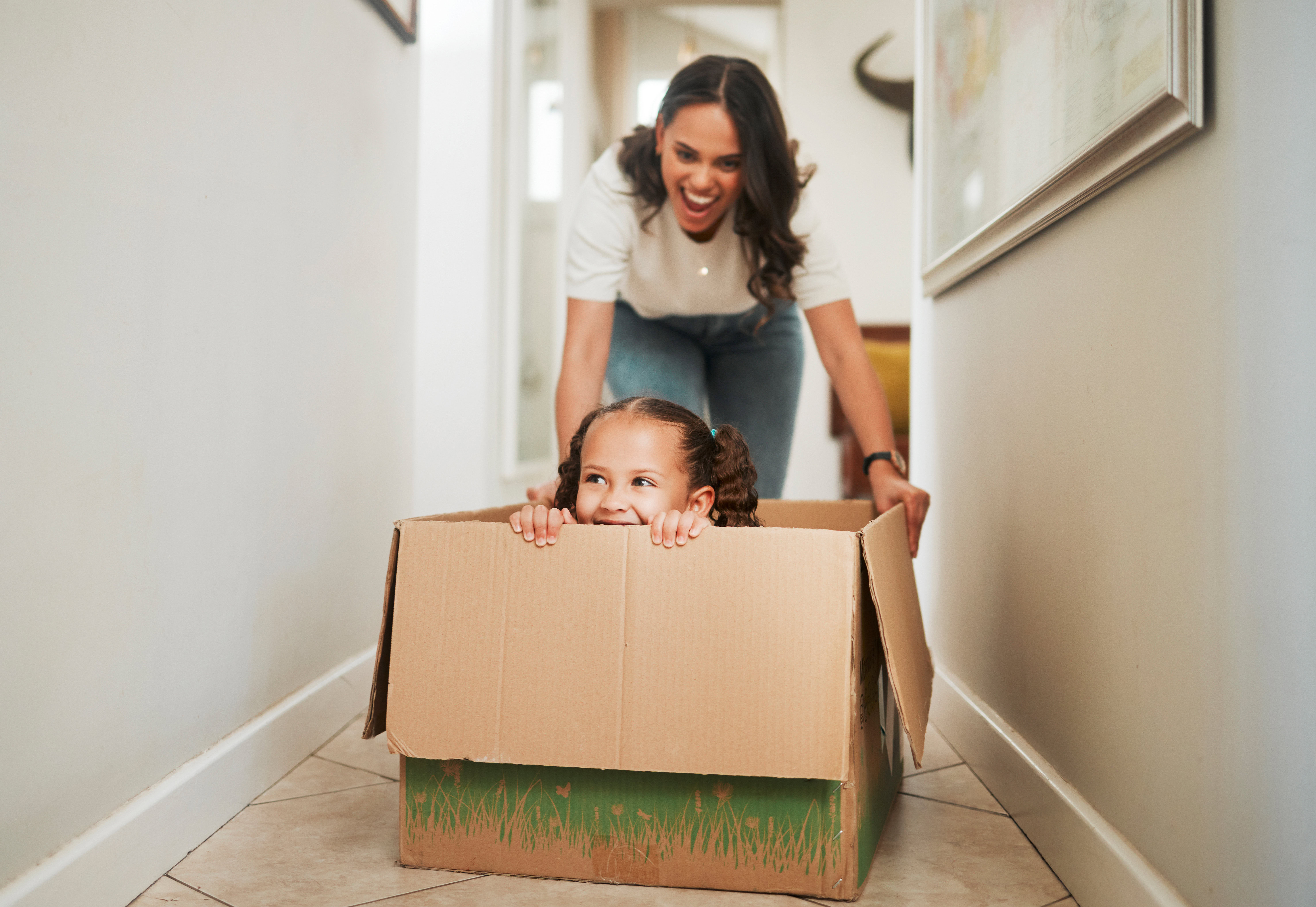 Happy mom and daughter playing with moving box