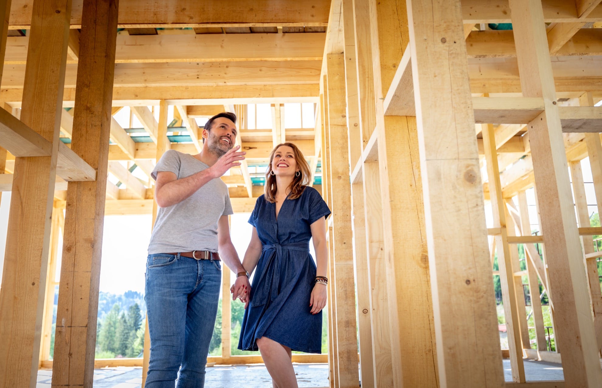 couple standing inside construction of house frame