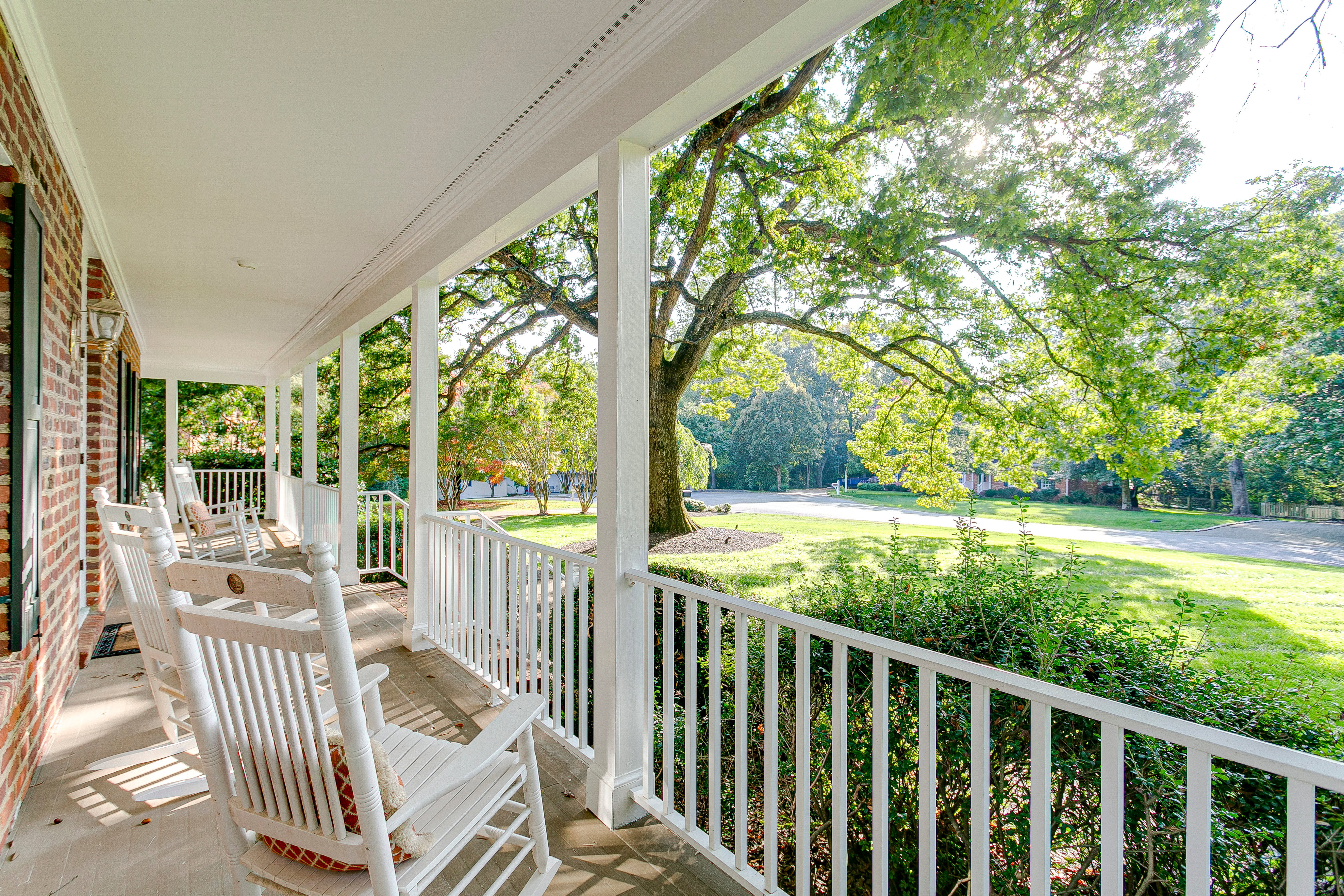 Southern front porch with white rocking chairs and greenery
