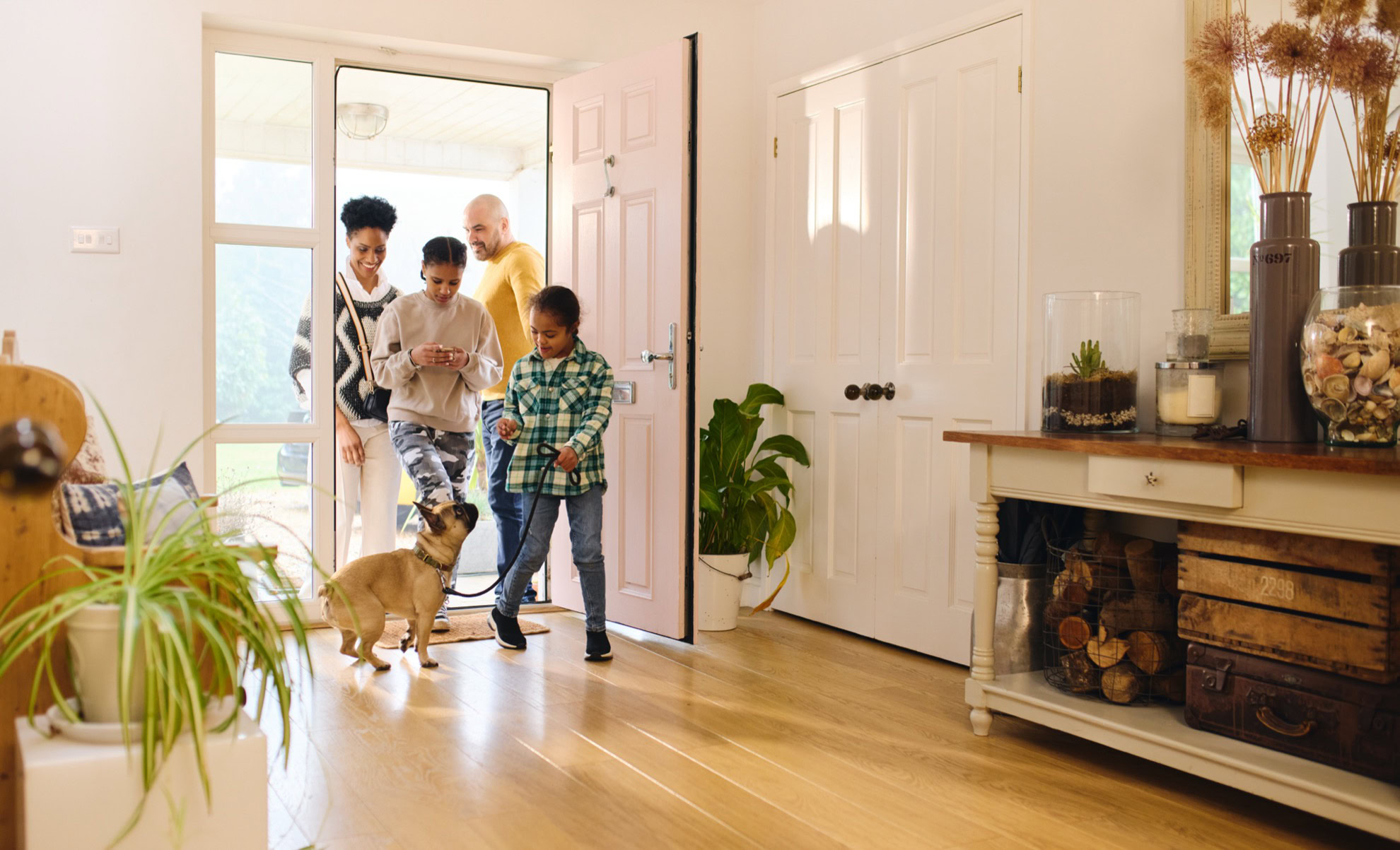Family entering new home with dog, enjoying mortgage approval process, happy homeowners.