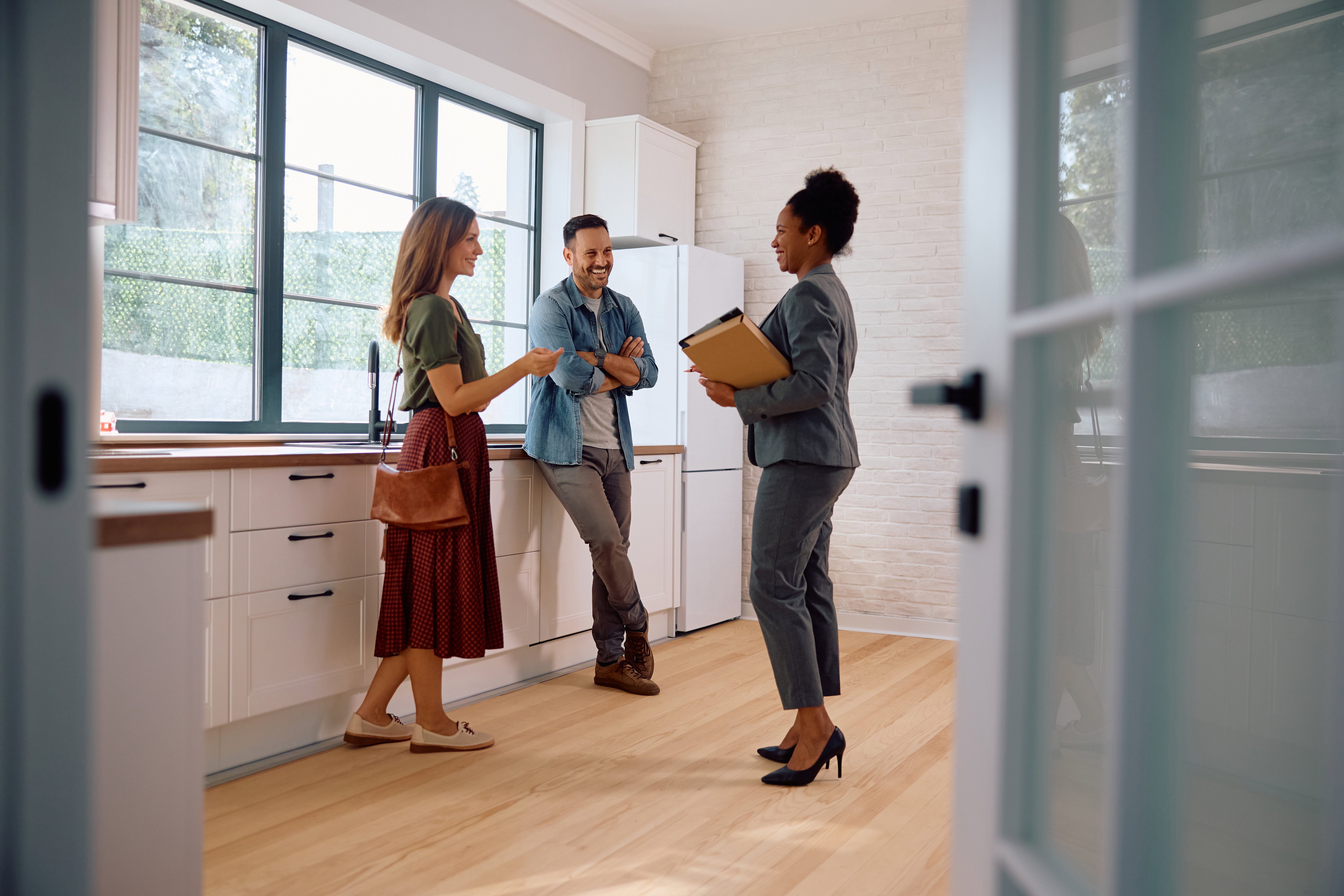 couple looking at home with realtor, standing in kitchen