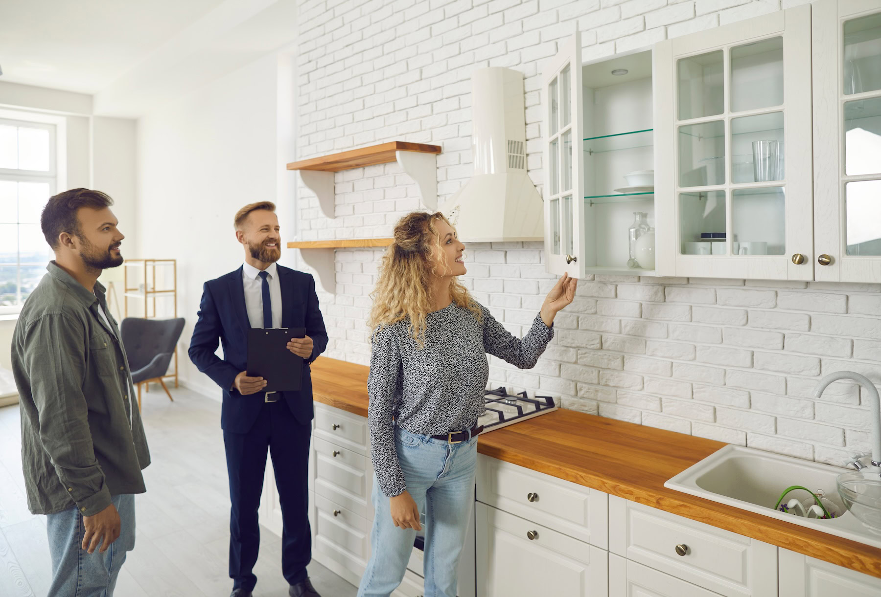 Female loan officer going over available loan options for a young couple|Young couple carrying boxes into new home|Young couple looking through home for sale with the help of an agent